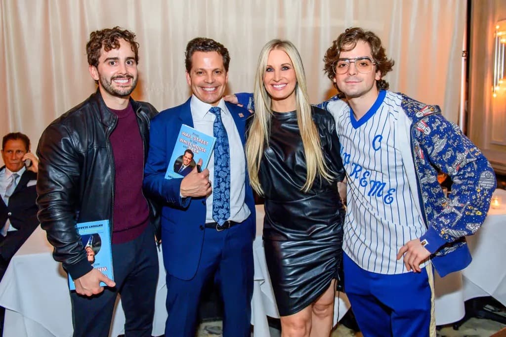 Four people smiling together at an event, with Anthony Scaramucci holding his book in the center.