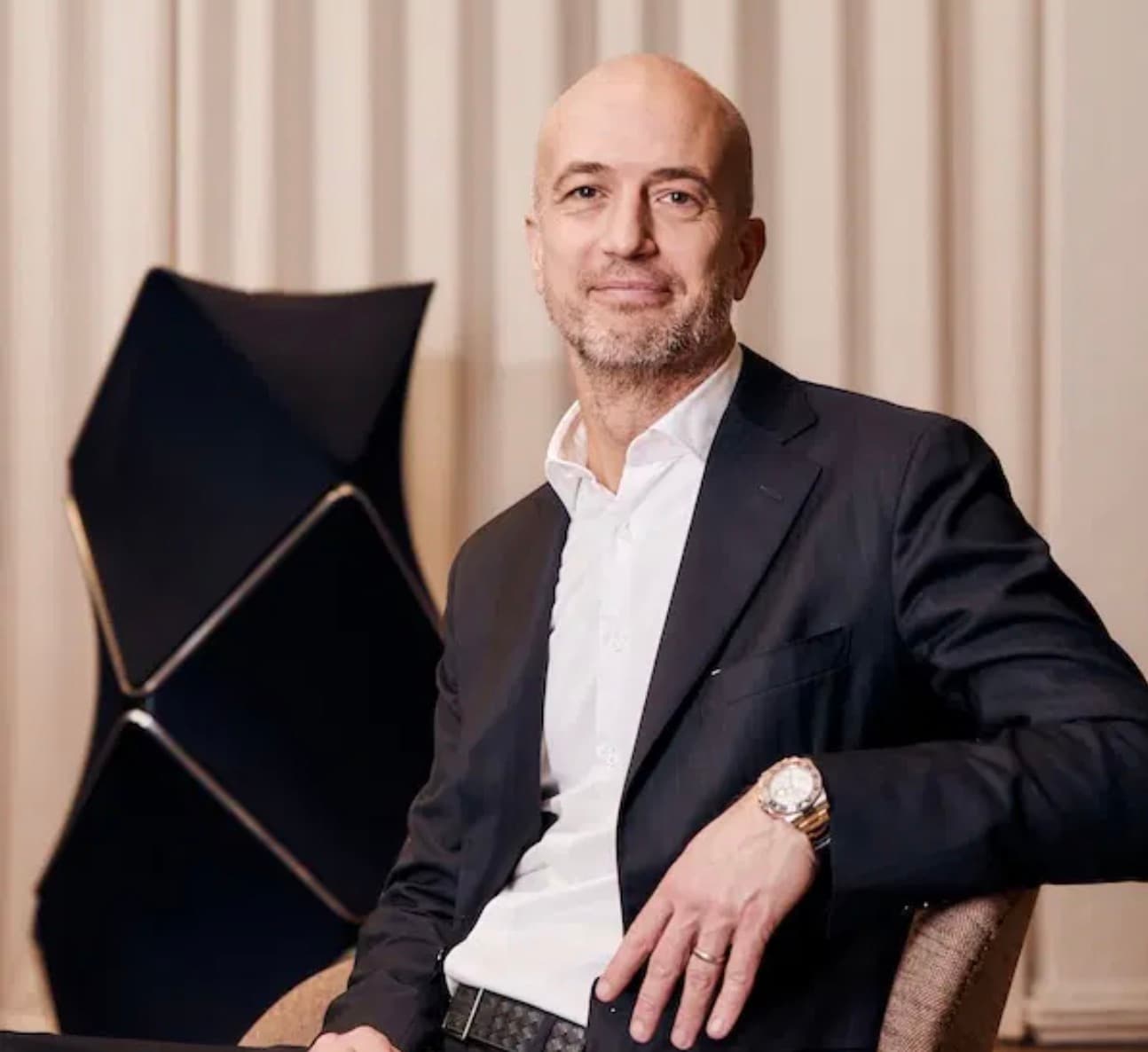 Bang & Olufsen chief operating officer Nikolaj Wendelboe seated beside one of the brand's sculptural black speakers.