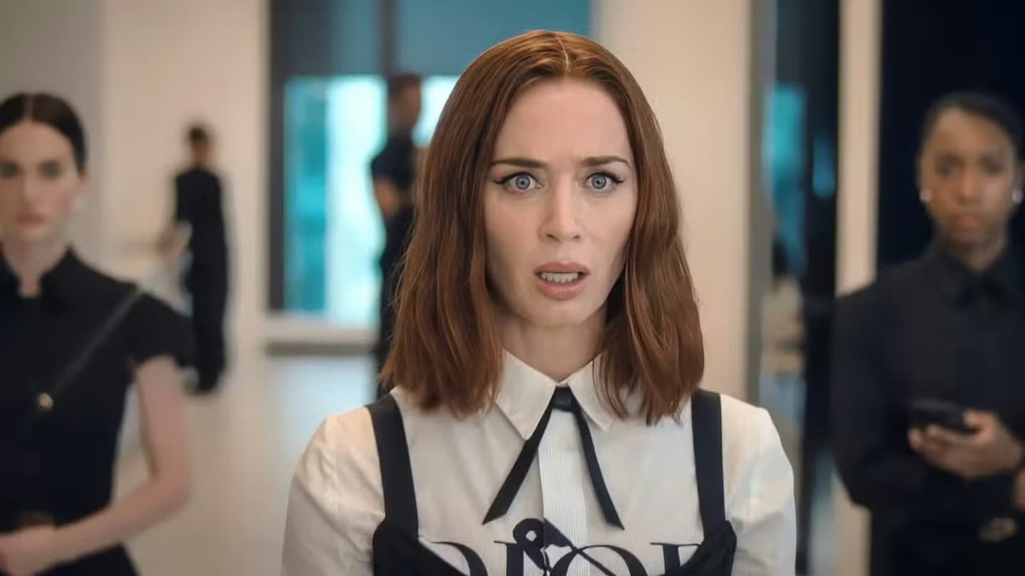 Emily Blunt looks startled in a white blouse and Dior harness top on the set of The Devil Wears Prada 2.