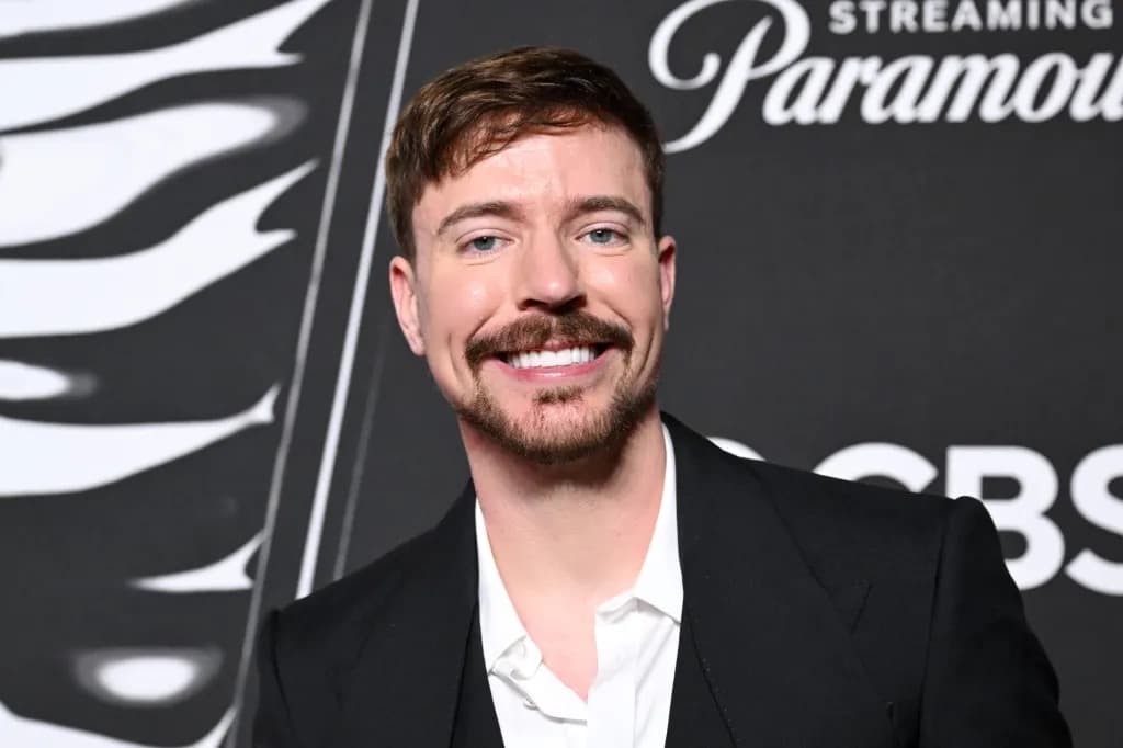 MrBeast (Jimmy Donaldson) smiling on a red carpet in a black suit and white shirt.