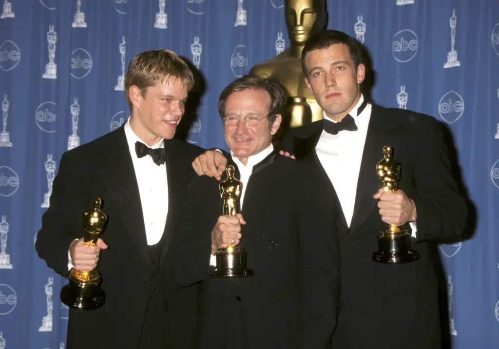 Matt Damon, Robin Williams and Ben Affleck holding Oscar statuettes together backstage.