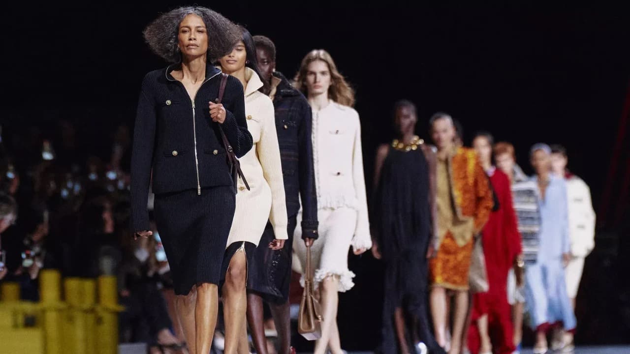 Models walk the runway at a Chanel fashion show in dark and cream tweed looks.