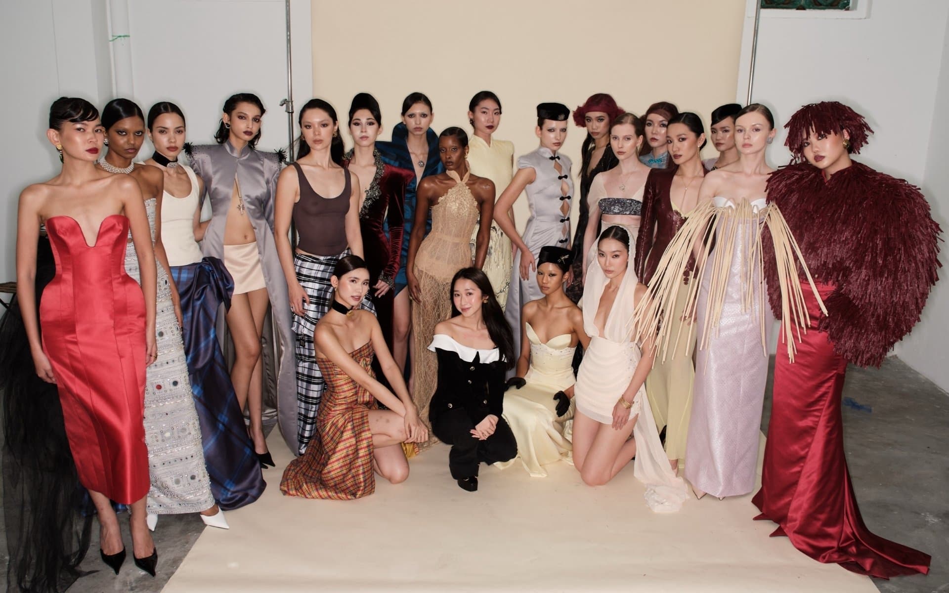 A large group of models backstage in a range of couture gowns and looks.