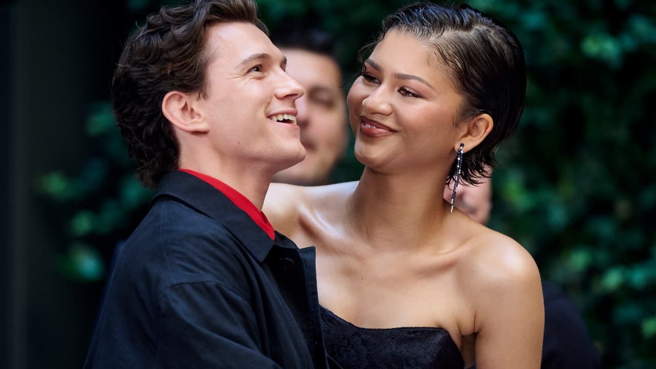 Tom Holland and Zendaya smile at each other closely at an outdoor event.
